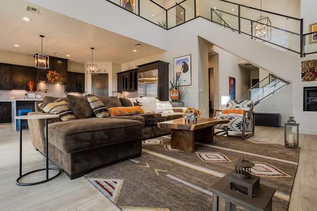 living room with an inviting chandelier, a high ceiling, and light wood-type flooring