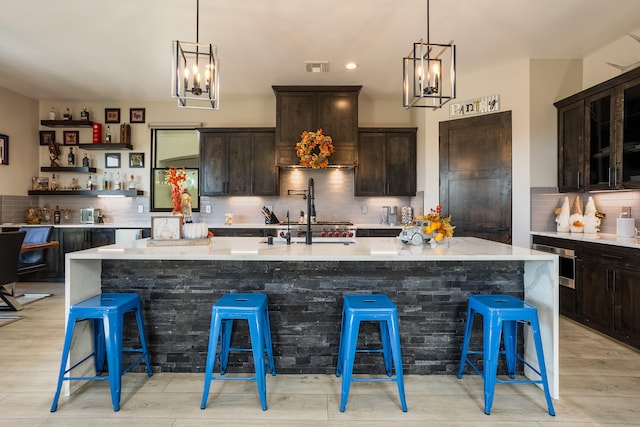 kitchen featuring a kitchen breakfast bar, dark brown cabinets, and an island with sink