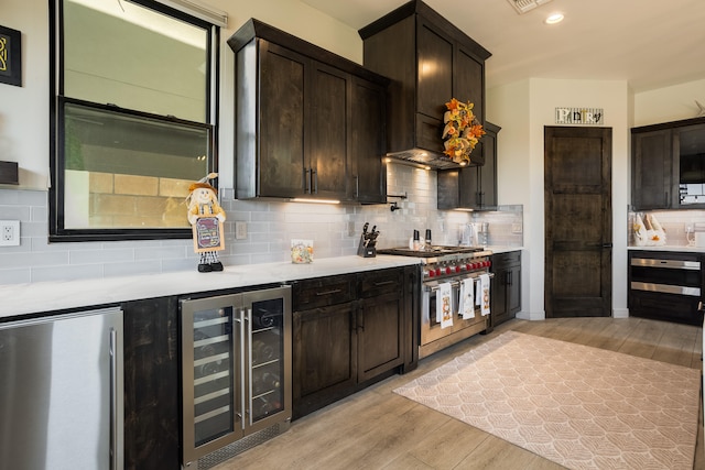 kitchen featuring wine cooler, light hardwood / wood-style flooring, stainless steel appliances, and tasteful backsplash