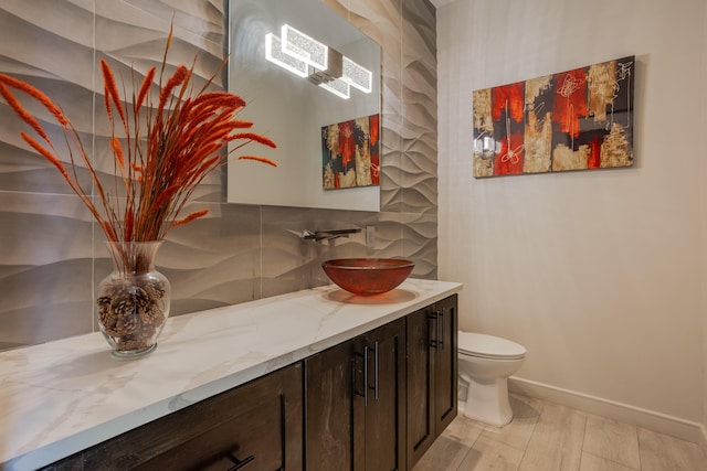 bathroom featuring vanity, toilet, and tasteful backsplash