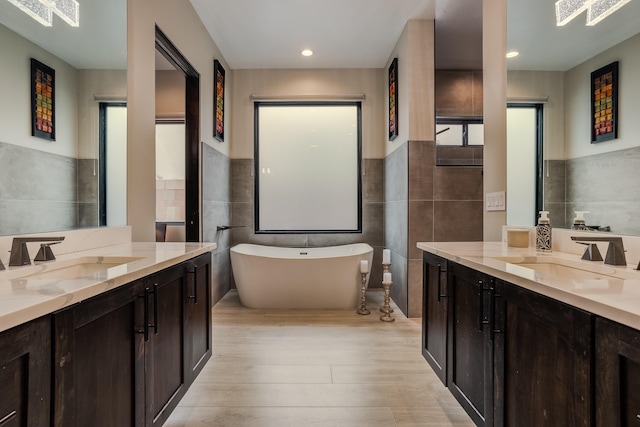 bathroom with vanity, tile walls, a bathtub, and hardwood / wood-style flooring