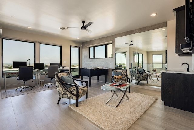 living room with sink, light hardwood / wood-style floors, and ceiling fan