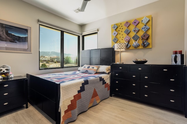 bedroom featuring light hardwood / wood-style flooring, a mountain view, and ceiling fan