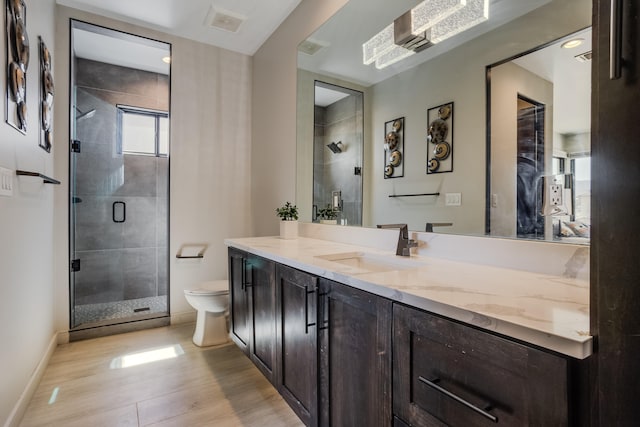 bathroom with a shower with door, vanity, wood-type flooring, and toilet