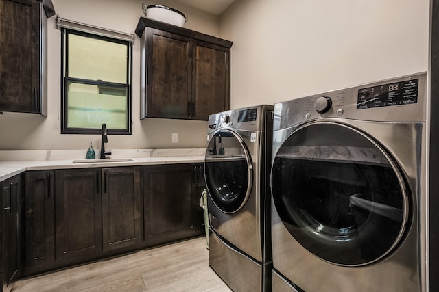 washroom featuring sink, light hardwood / wood-style flooring, independent washer and dryer, and cabinets