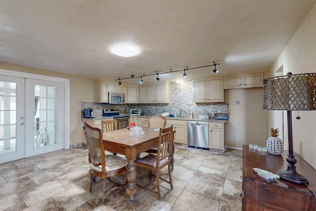 dining space featuring french doors, rail lighting, and sink