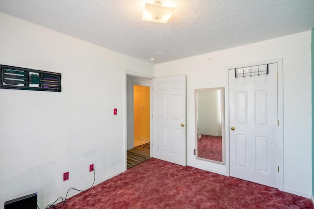 unfurnished bedroom with dark carpet, a textured ceiling, and a closet