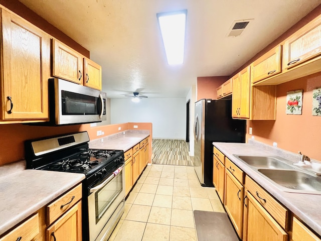 kitchen featuring ceiling fan, sink, light tile patterned flooring, and stainless steel appliances