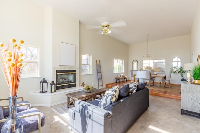 living room with ceiling fan, a tiled fireplace, and high vaulted ceiling