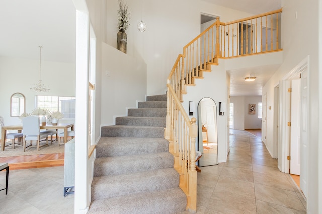 stairway featuring a high ceiling, tile patterned flooring, and a chandelier