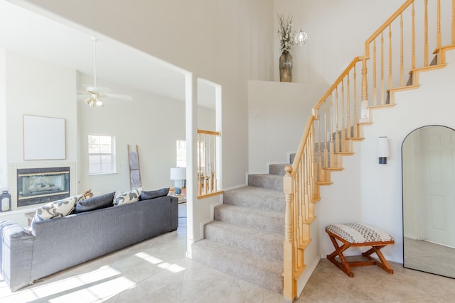 staircase with ceiling fan, a high ceiling, and tile patterned floors