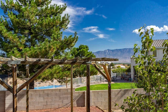 view of playground featuring a mountain view, a pergola, and a patio area