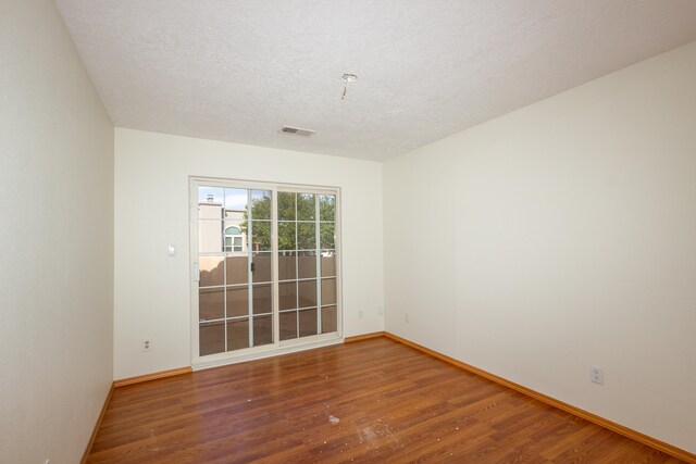 unfurnished room with a textured ceiling and hardwood / wood-style floors