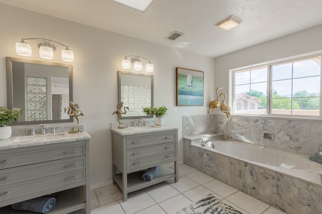 bathroom featuring tiled tub, vanity, tile patterned flooring, and a textured ceiling