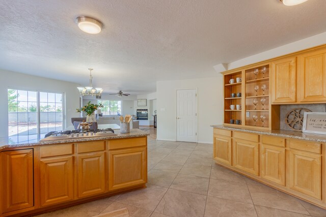 kitchen with ceiling fan with notable chandelier, pendant lighting, stainless steel gas cooktop, light tile patterned floors, and a textured ceiling