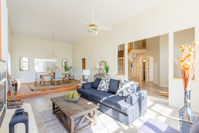 living room with ceiling fan with notable chandelier, light wood-type flooring, and a towering ceiling