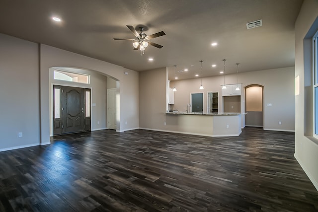 unfurnished living room featuring ceiling fan, sink, and dark wood-type flooring