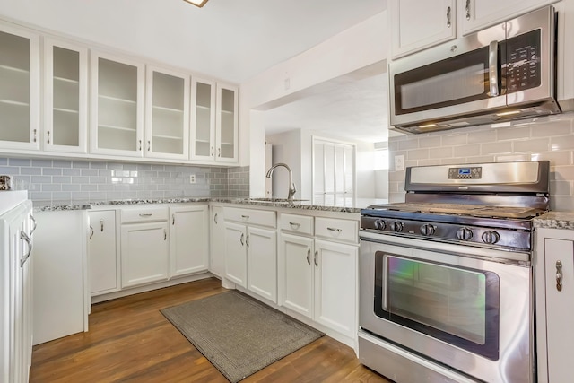 kitchen featuring a sink, appliances with stainless steel finishes, wood finished floors, and white cabinets