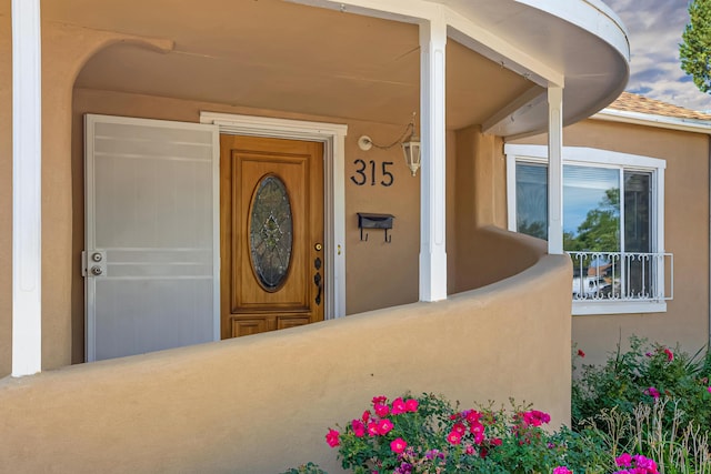 entrance to property featuring stucco siding and a shingled roof