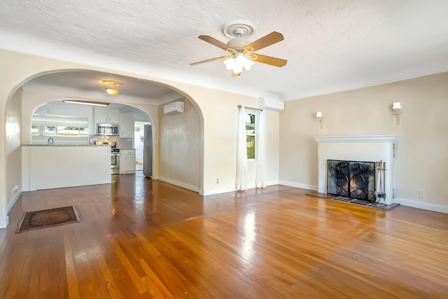 unfurnished living room featuring hardwood / wood-style flooring, ceiling fan, and a textured ceiling