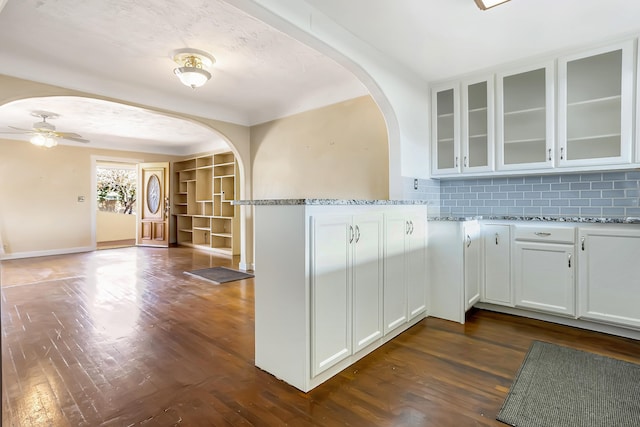 kitchen with decorative backsplash, dark hardwood / wood-style flooring, white cabinetry, and light stone counters