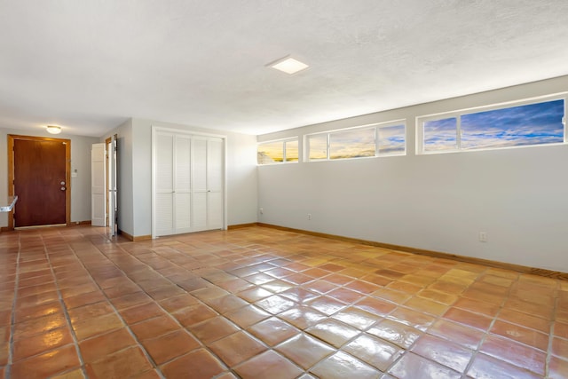 tiled spare room with a textured ceiling and baseboards