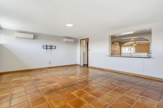 spare room featuring arched walkways, a wall mounted air conditioner, baseboards, and a sink