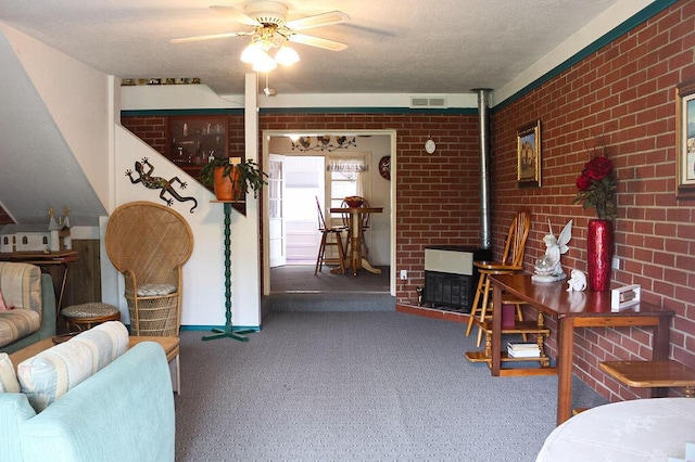 interior space featuring ceiling fan, brick wall, a textured ceiling, and a wood stove