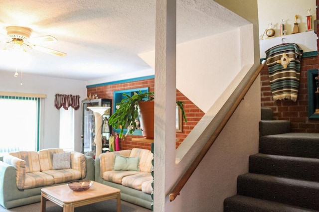 living room with ceiling fan, a fireplace, and a textured ceiling