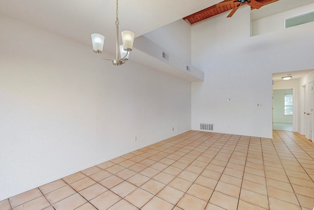 tiled empty room with a towering ceiling and ceiling fan with notable chandelier