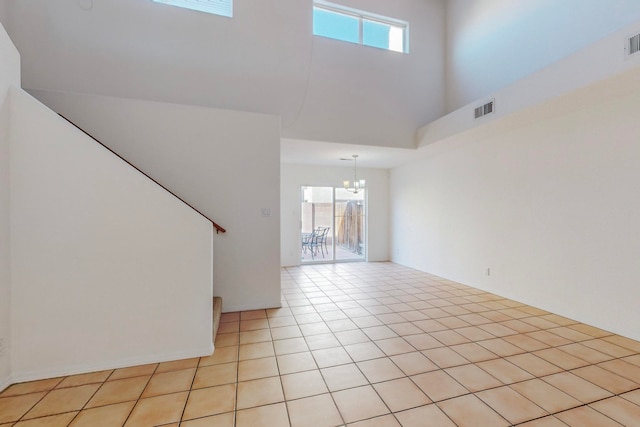 interior space featuring a high ceiling, light tile patterned flooring, an inviting chandelier, and plenty of natural light