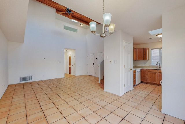 kitchen featuring a high ceiling, hanging light fixtures, white dishwasher, light tile patterned flooring, and ceiling fan with notable chandelier