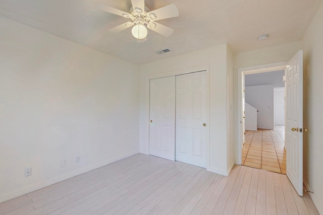 unfurnished bedroom with light hardwood / wood-style floors, a closet, and ceiling fan