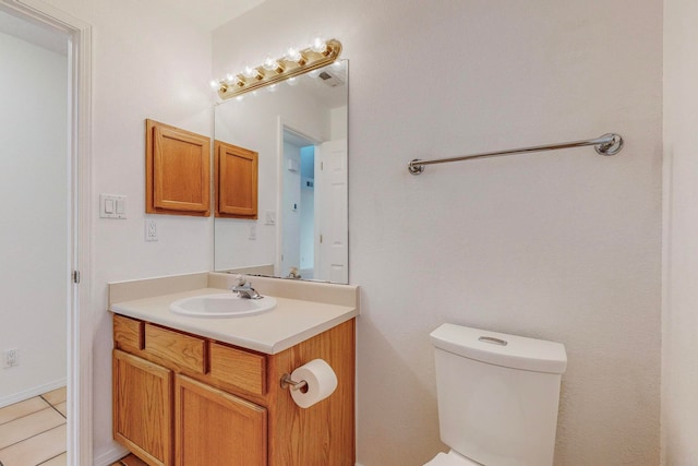 bathroom with toilet, vanity, and tile patterned flooring