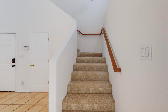 stairs featuring high vaulted ceiling and tile patterned floors