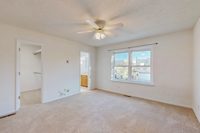 interior space with light carpet, a textured ceiling, a spacious closet, and ceiling fan