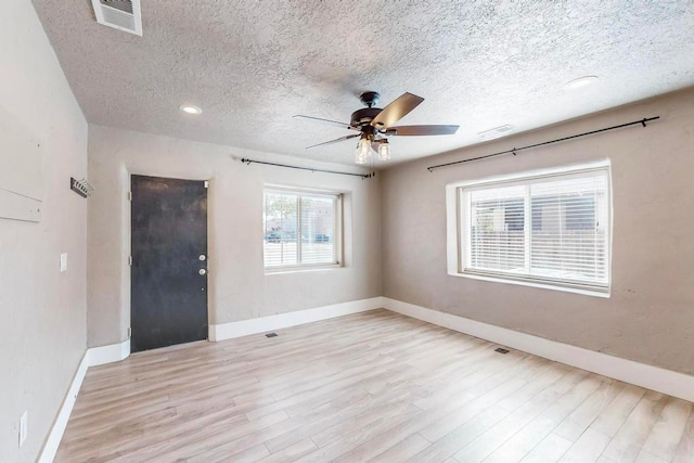 empty room featuring ceiling fan, a textured ceiling, and light wood-type flooring