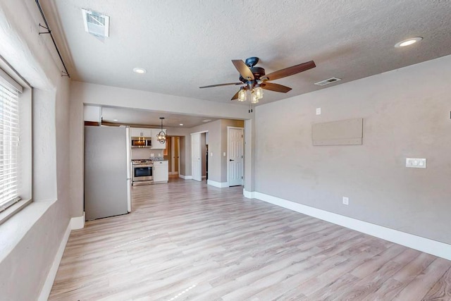 unfurnished living room featuring ceiling fan, light hardwood / wood-style floors, and a textured ceiling