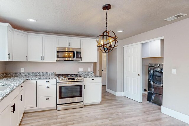 1139 Forrester Ave NW, Albuquerque, NM 87104 - kitchen featuring washer / clothes dryer, stainless steel appliances, visible vents, an inviting chandelier, and light wood-style flooring