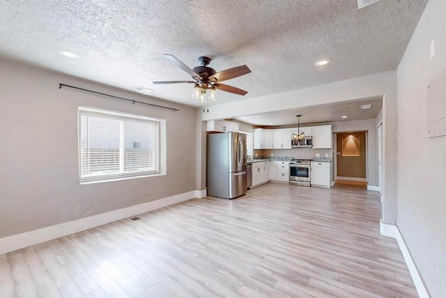 unfurnished living room featuring light wood-type flooring, ceiling fan, and a textured ceiling