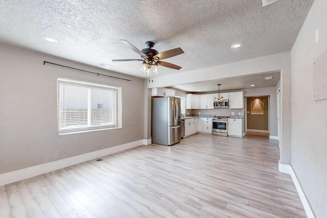 1139 Forrester Ave NW, Albuquerque, NM 87104 - unfurnished living room featuring a textured ceiling, baseboards, light wood finished floors, ceiling fan, and visible vents