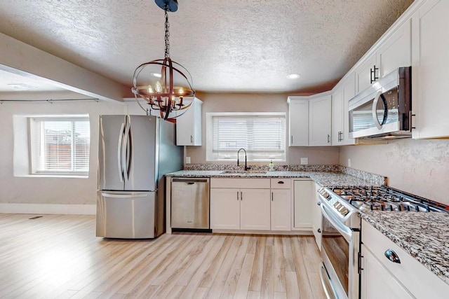 kitchen featuring appliances with stainless steel finishes, light wood-type flooring, sink, and white cabinets