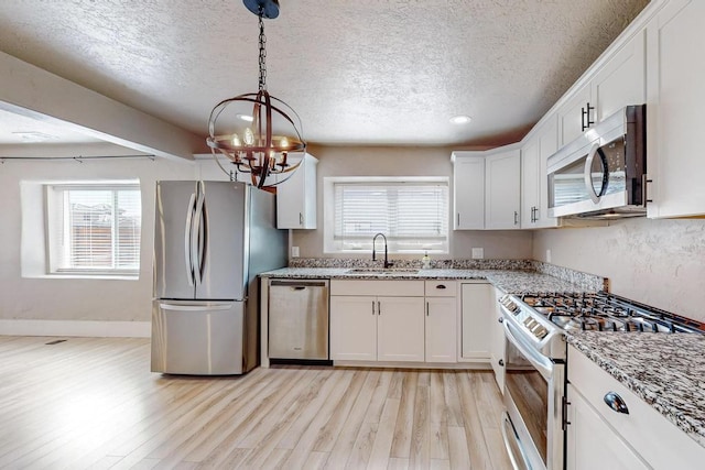 1139 Forrester Ave NW, Albuquerque, NM 87104 - kitchen featuring a textured ceiling, light wood-style floors, appliances with stainless steel finishes, and a sink