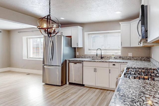 1139 Forrester Ave NW, Albuquerque, NM 87104 - kitchen featuring a notable chandelier, a textured ceiling, light wood finished floors, a sink, and appliances with stainless steel finishes