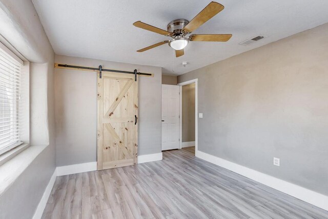 1139 Forrester Ave NW, Albuquerque, NM 87104 - spare room featuring ceiling fan, a barn door, baseboards, and visible vents