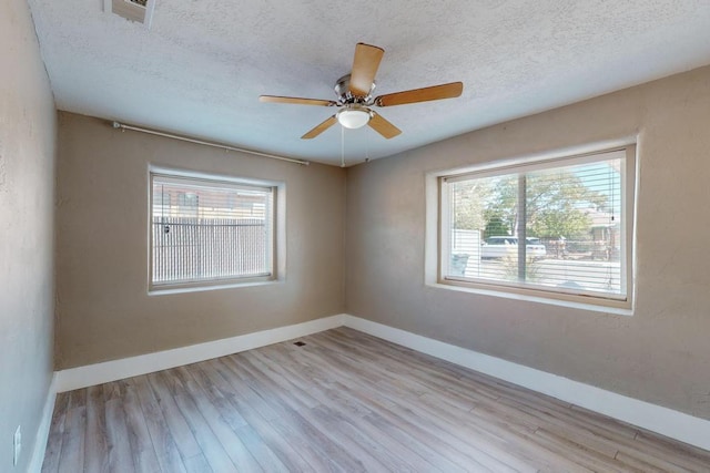 empty room with ceiling fan, a textured ceiling, and light wood-type flooring