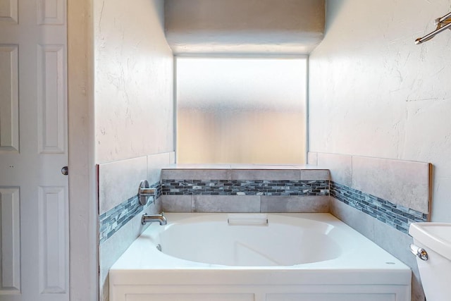 bathroom featuring toilet and a washtub