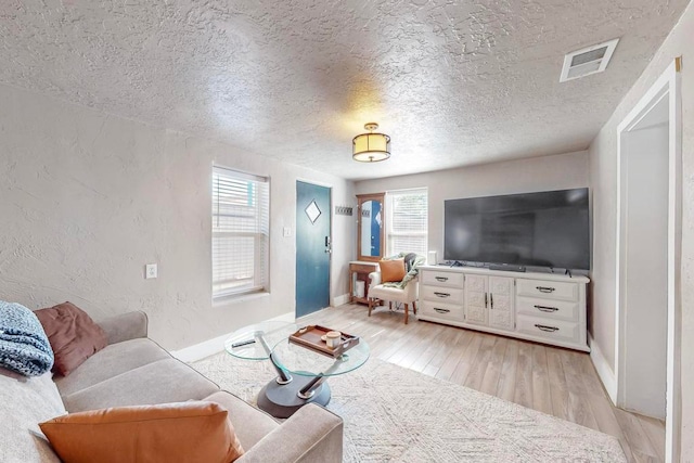 living room with a healthy amount of sunlight, light hardwood / wood-style floors, and a textured ceiling