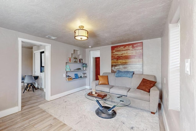 1139 Forrester Ave NW, Albuquerque, NM 87104 - living area featuring a textured ceiling, visible vents, baseboards, and wood finished floors