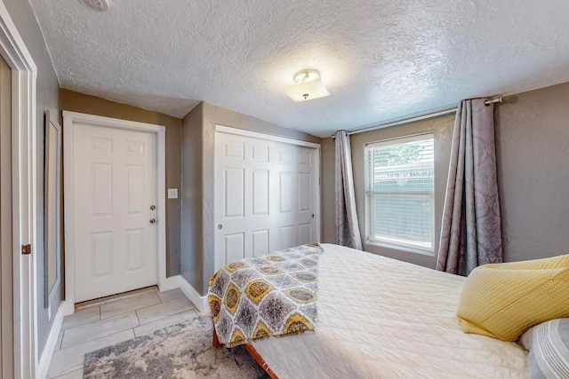 bedroom with a closet, light tile patterned floors, and a textured ceiling